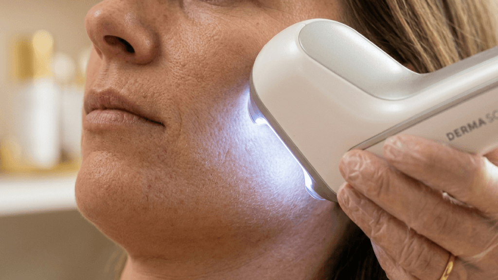 Close-up of professional skin analysis device scanning a woman’s cheek during a facial consultation