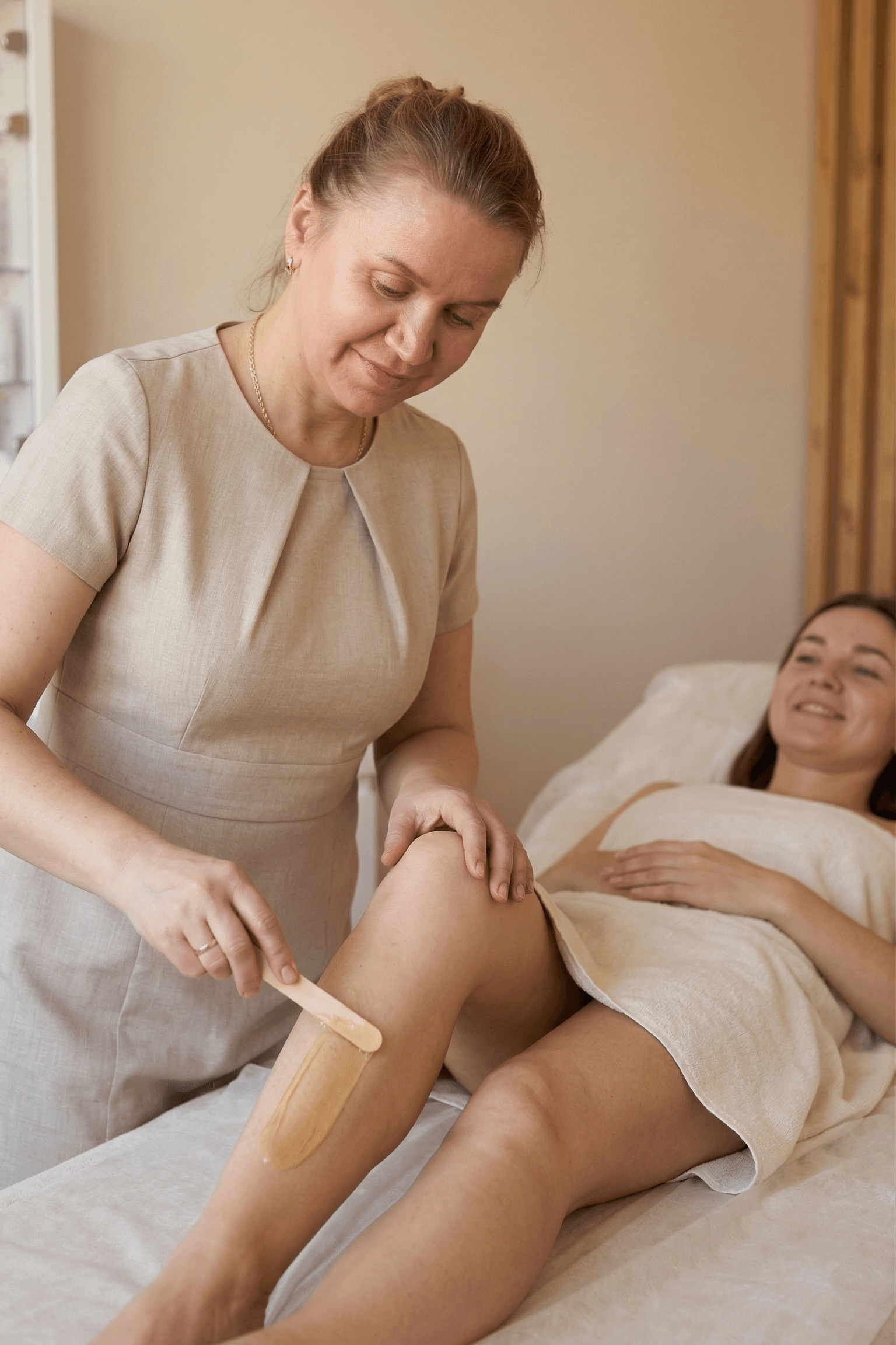 Therapist applying warm wax to a client’s lower leg during a professional waxing treatment