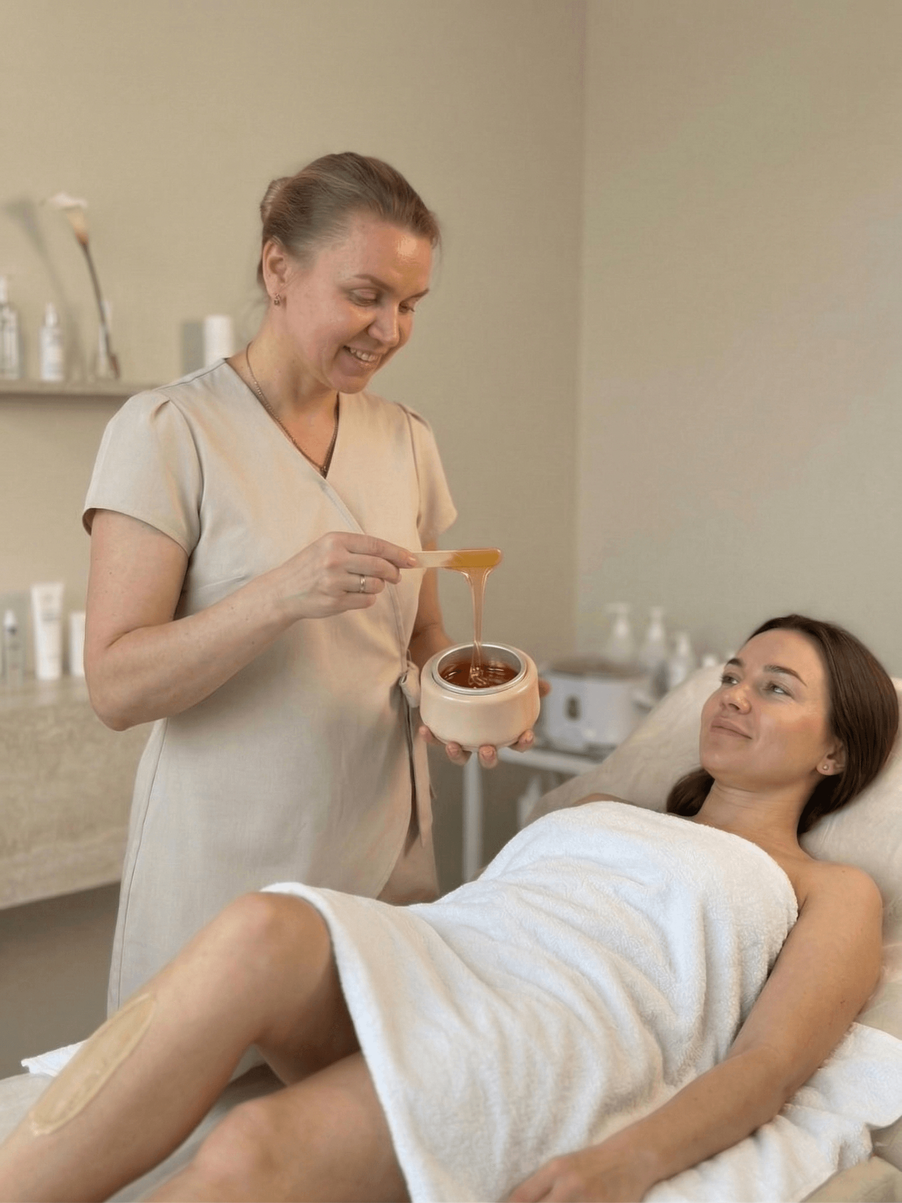 Therapist preparing warm wax beside a client during a professional waxing appointment
