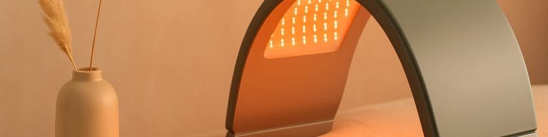 Soft amber-rose LED panel ambient glow on beige. Dermalux LED therapy. Skincare & Waxing Kirkham.