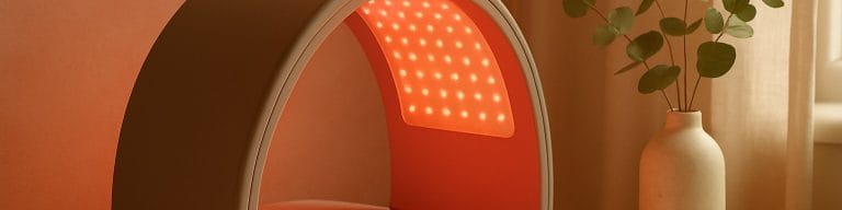 Professional LED panel with red-pink ambient glow on treatment bed. Dermalux LED therapy. Skincare & Waxing Kirkham.